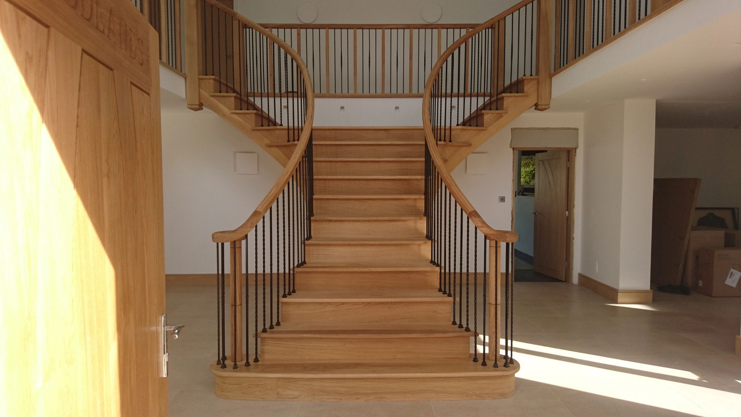 Bespoke curved timber staircase crafted in York featuring handcrafted continuous handrail and turned balusters